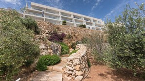 A multi-story building with a stone retaining wall and a stone staircase leading up to it. - Property With Pool Access - Xaghra Near Marsalforn (Xaghra)
