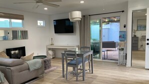 Een moderne woonkamer met een bank, televisie, bureau en eethoek.