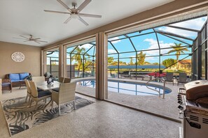 A spacious patio with a pool, outdoor furniture, and a grill area. - Anchored Out - Waterfront Rental in Great Location - Vesteva (Cape Coral)
