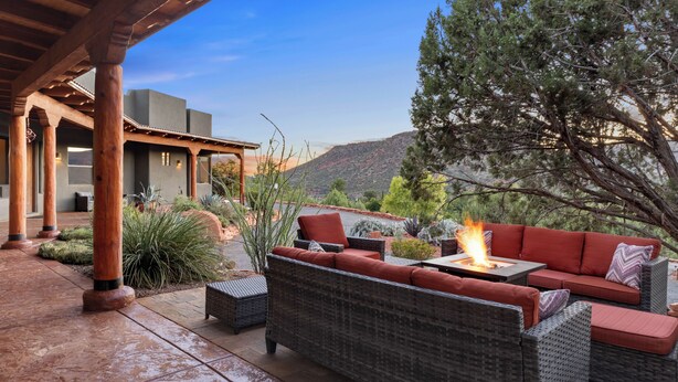 Une terrasse extérieure aménagée avec des meubles en osier, un foyer et une vue sur une montagne.