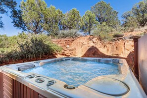 Un bain à remous situé dans un cadre naturel, avec un décor rocheux et des arbres.