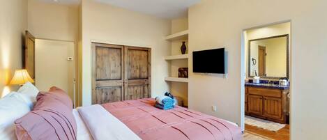 A bedroom with a bed, a ceiling fan, a TV, and a wooden wardrobe.