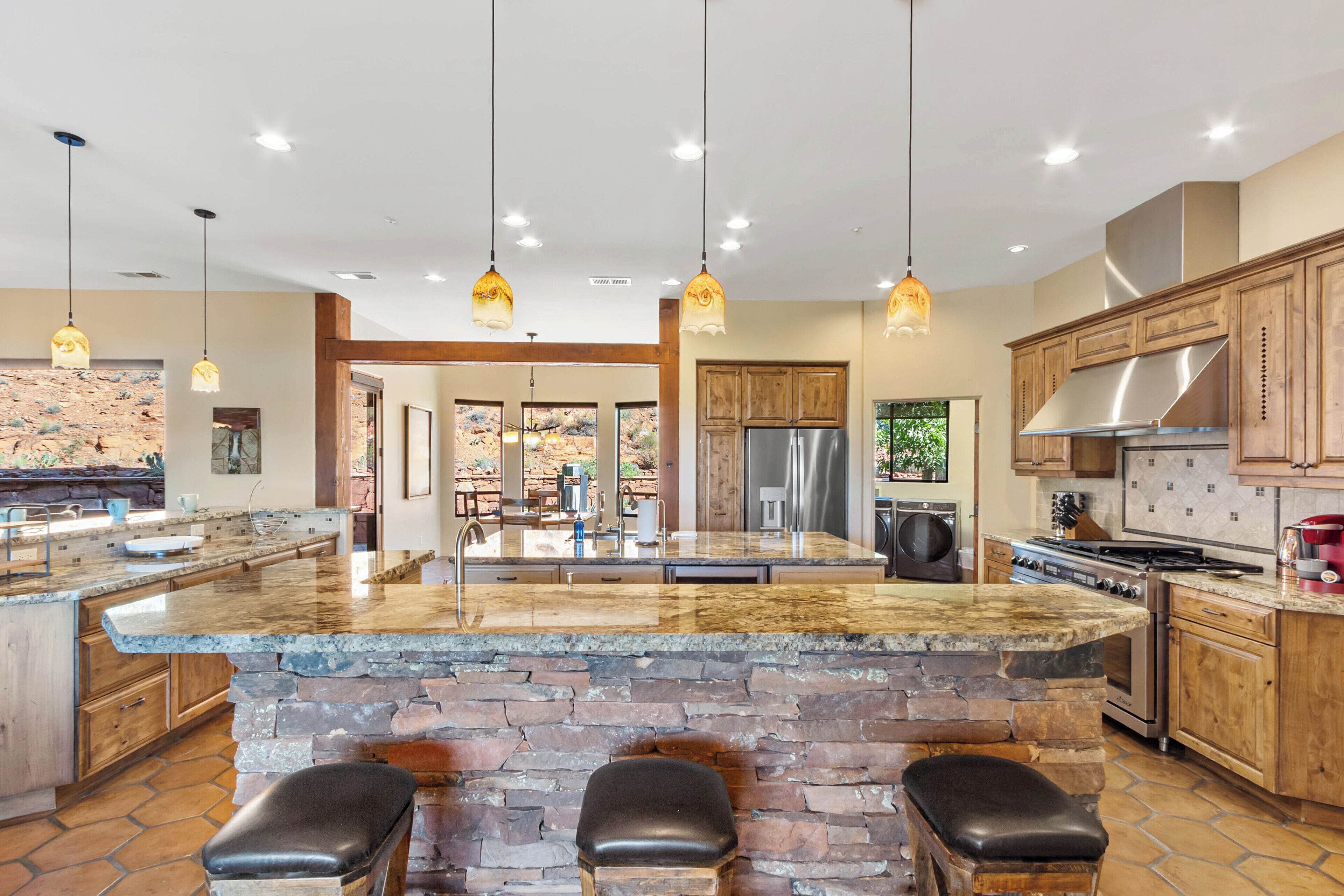 A spacious kitchen with a large island, wooden cabinets, and a stone accent wall.