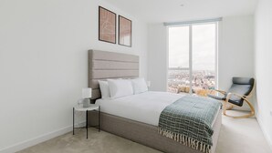 Une chambre moderne avec un grand lit, une table de chevet, une chaise et une vue sur la ville par une grande fenêtre.