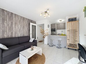 A modern living room with a sofa, a coffee table, and a kitchen area with a bar.
