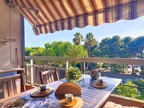 Ein Balkon mit Tisch für zwei Personen, mit Blick auf eine reizvolle Landschaft mit Bäumen und einer Straße.