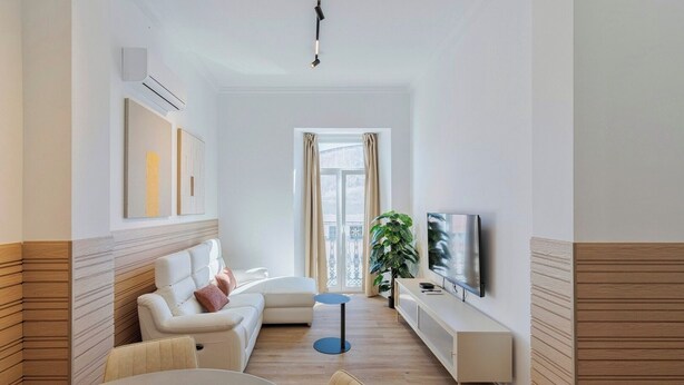 A modern living room with a sofa, TV, and dining area.