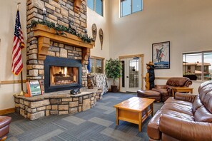 A stone fireplace with a mantel, a leather couch, a coffee table, and a flag.