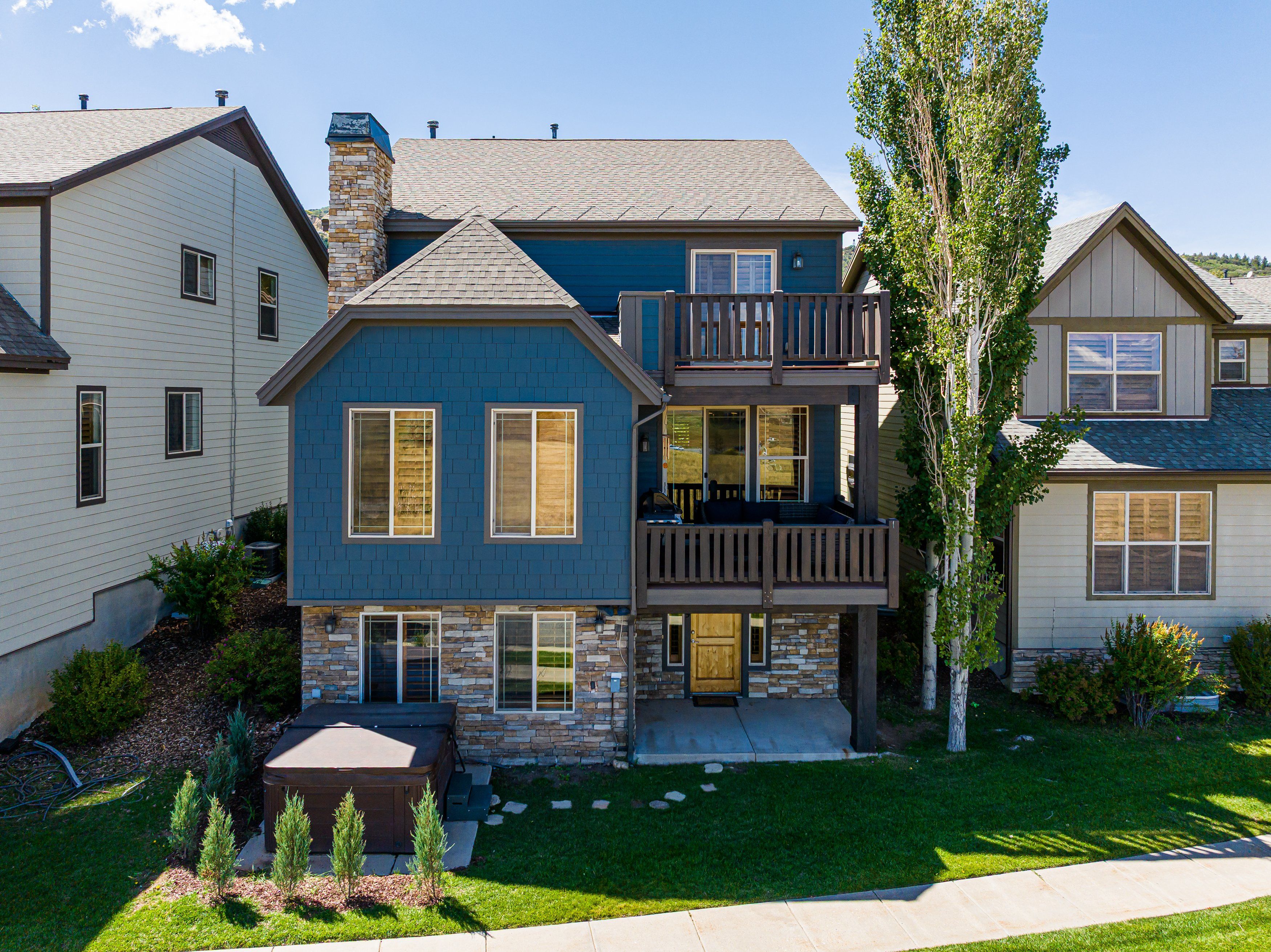 A two-story house with a stone facade, a balcony, and a well-maintained lawn.
