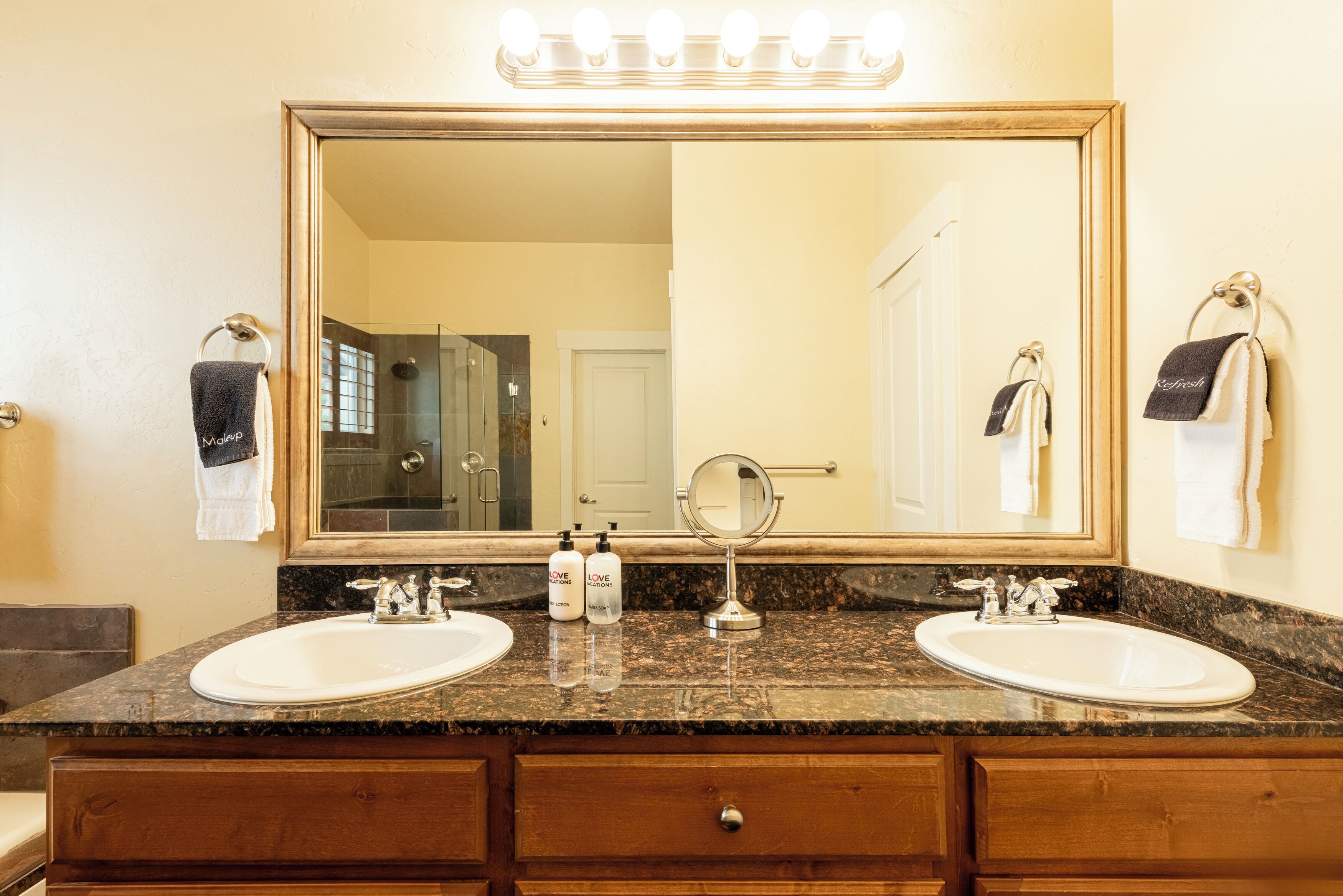 A bathroom with two sinks, a large mirror, and a vanity with a wooden cabinet.