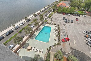 Une piscine avec des chaises longues, un parking et une vue sur le bord de l’eau.