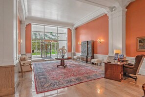 Un hall d’entrée spacieux, agrémenté d’un grand tapis, d’un bureau avec une chaise et d’une statue.