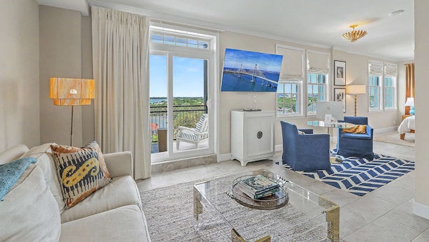 A modern living room with a sofa, armchairs, a coffee table, and a view of a balcony.