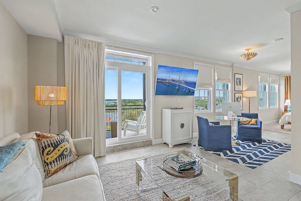A modern living room with a sofa, armchairs, a coffee table, and a view of a balcony.