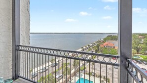 A balcony with a view of a body of water, a street, and residential buildings.