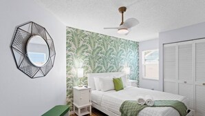 Ein Schlafzimmer mit einem Bett, Nachttischen, einem Spiegel, einem Deckenventilator und einem Kleiderschrank.