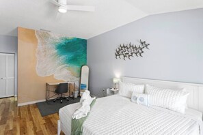 A bedroom with a bed, a desk, a chair, a wall art of waves, a ceiling fan, and a decorative wall piece. - ⭐ Heated pool, Putting Green + Arcade Near IMG (Bradenton)