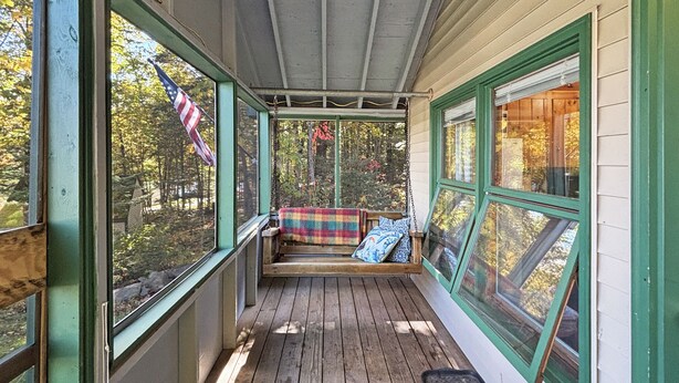 A covered porch with a wooden bench and a plaid blanket. - Hedgehog (Wilson Pond Cabins) (Greenville)