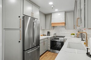 Une cuisine moderne dotée d’appareils électroménagers en acier inoxydable, de meubles blancs et d’un plan de travail en marbre.