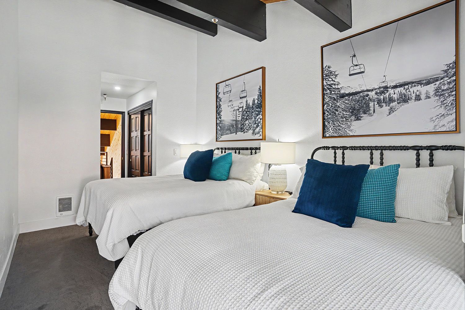 Une chambre d’hôtel avec deux lits, une table de chevet, une lampe et deux tableaux encadrés au mur.