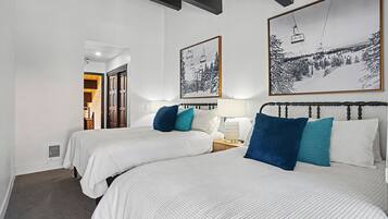 Une chambre d’hôtel avec deux lits, une table de chevet, une lampe et deux tableaux encadrés au mur.