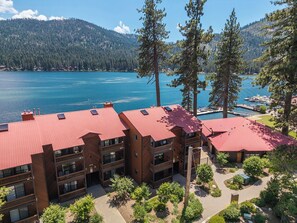 Un hôtel à plusieurs étages, avec un toit rouge, situé près d’un lac où sont amarrés des bateaux, et entouré d’arbres et de montagnes.