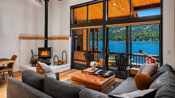 A modern living room with a fireplace, large windows, and a view of a lake. - Townhouse w/Lake View #254 at Donner Lake Village (Truckee)