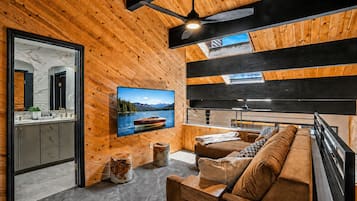 A modern interior with a wooden ceiling, a mounted TV, a sofa, and a dining area.
