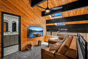 Un intérieur moderne avec un plafond en bois, un téléviseur fixé au mur, un canapé et un coin repas.