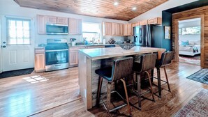 Una cocina moderna con armarios de madera, electrodomésticos de acero inoxidable y una isla grande con taburetes de bar.