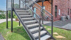 Un edificio moderno con fachada de ladrillo y una escalera metálica que conduce a un área cubierta.