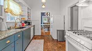 A modern kitchen with a granite countertop, a stainless steel refrigerator, and a gas stove. - Charming 3BR Downtown Natchitoches Home, 1.5 Bath, Walking Distance to Front St (Natchitoches)