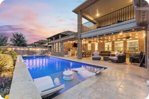 Ein zweistöckiges Haus mit Schwimmbad, Sitzgelegenheit im Freien und einem Balkon.