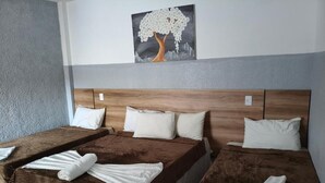 Ett hotellrum med två sängar, var och en med ett brunt överkast och vita kuddar. På väggen ovanför sängarna hänger en tavla som föreställer ett träd.