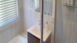 Ein modernes Badezimmer mit Duschkabine aus Glas, einem weißen Waschbecken und einem Spiegel.