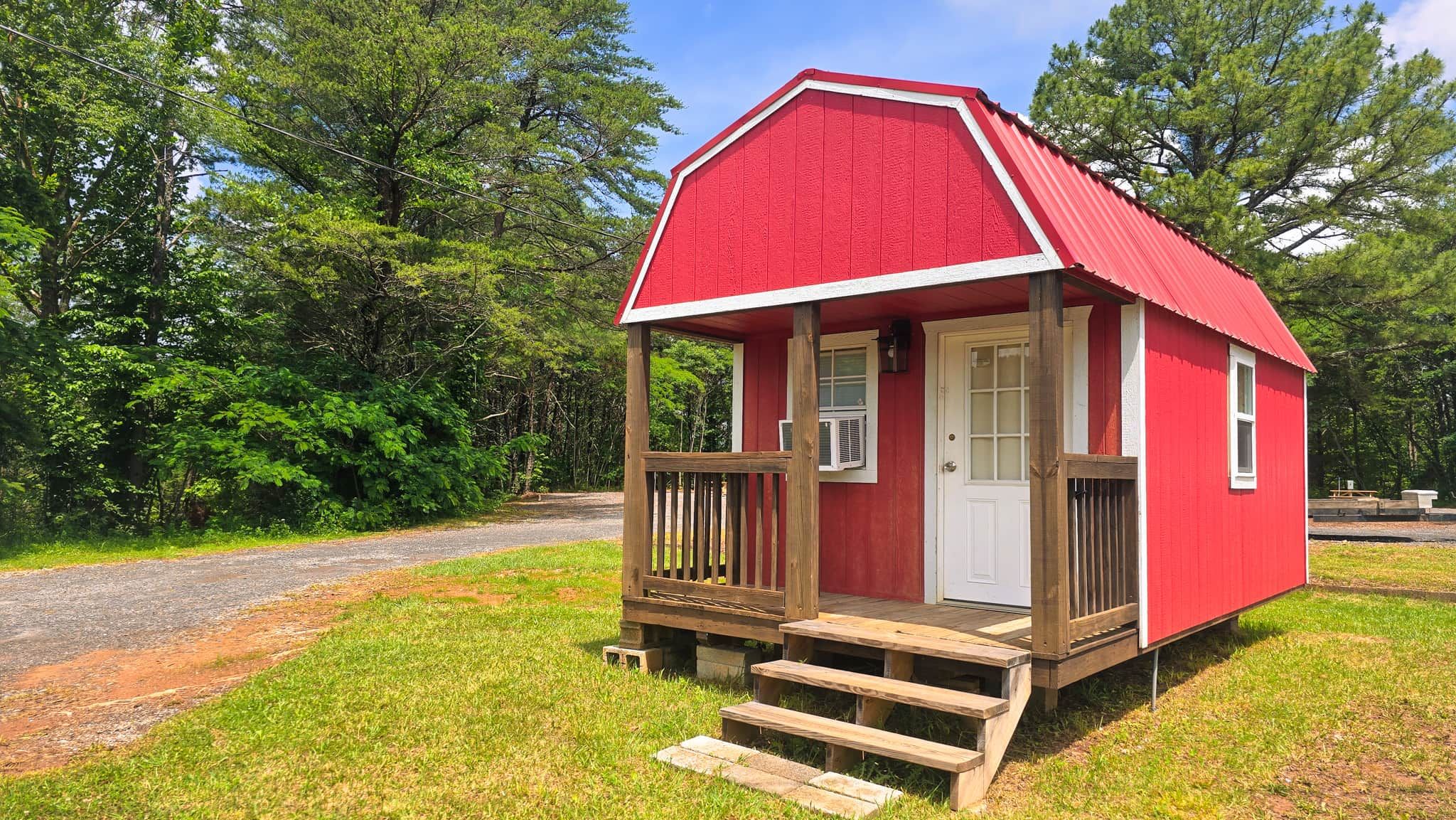 A small red cabin with a white door and a small porch with steps.