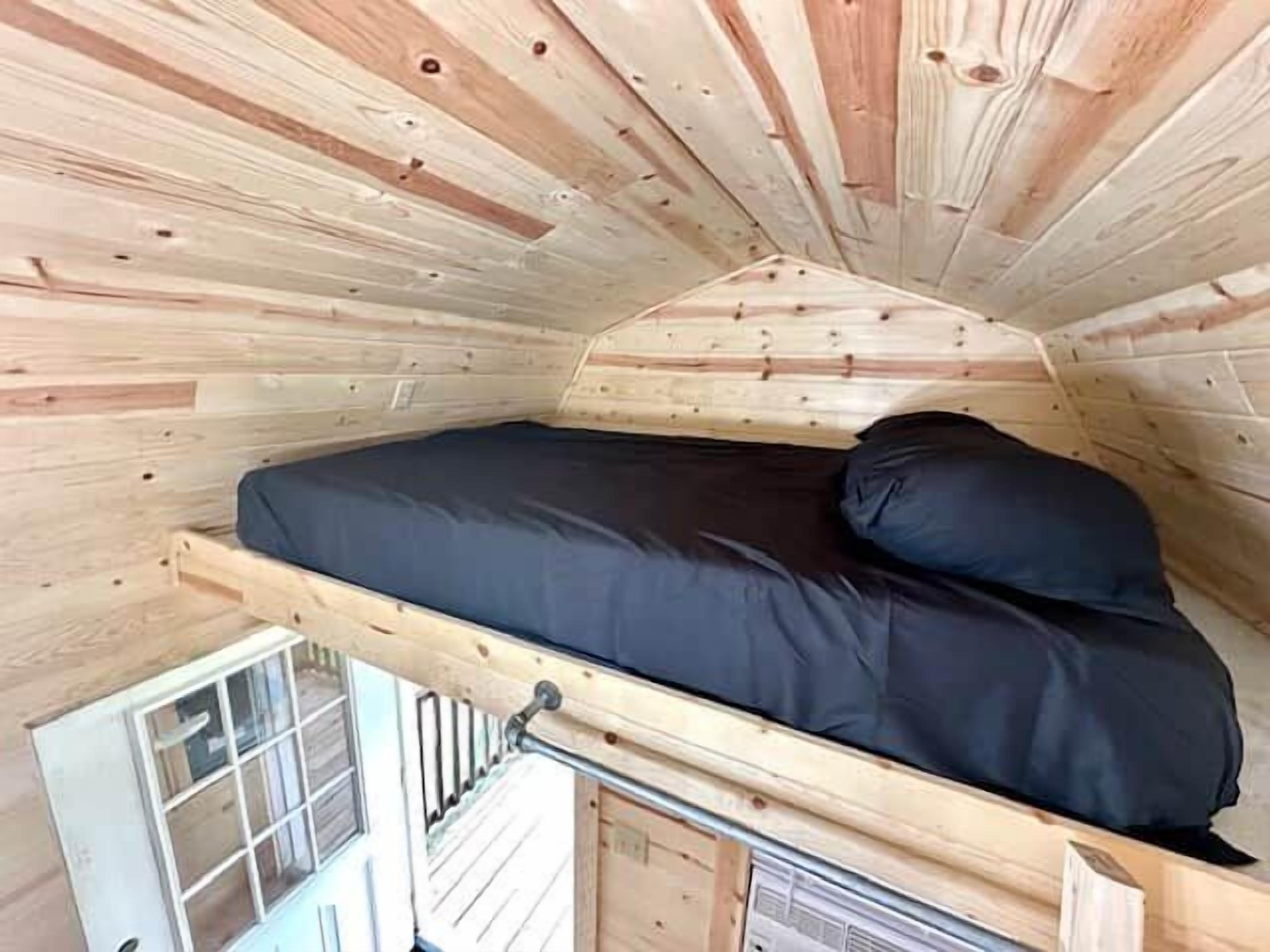 Una habitación pequeña y cerrada con una cama individual, una ventana y un radiador.