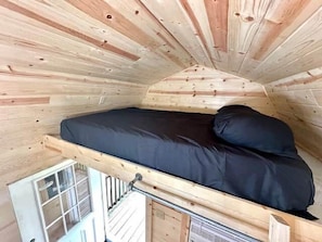 Une petite pièce fermée, avec un lit simple, une fenêtre et un radiateur.