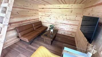 A cabin interior with a sofa, a small table, a TV, and a wooden wall.