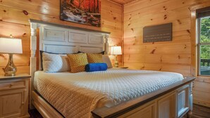 Una stanza con rivestimento in legno, un letto, due lampade da comodino, un quadro e una targa appesa al muro.