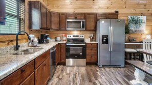 Una cocina con gabinetes de madera, un refrigerador de acero inoxidable, un microondas y un horno empotrado.