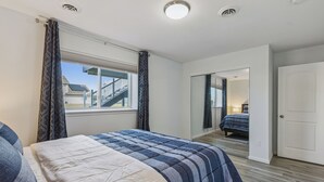 Une chambre à coucher avec un grand lit, une fenêtre avec des rideaux, une porte et une vue sur un escalier menant à l’extérieur.