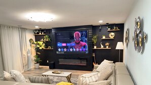 Un salon moderne doté d’un grand téléviseur à écran plat, d’un canapé, d’une table basse et d’objets décoratifs.