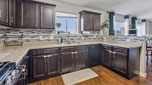 Une cuisine moderne avec des meubles en bois foncé, un plan de travail en granit et un grand îlot central.