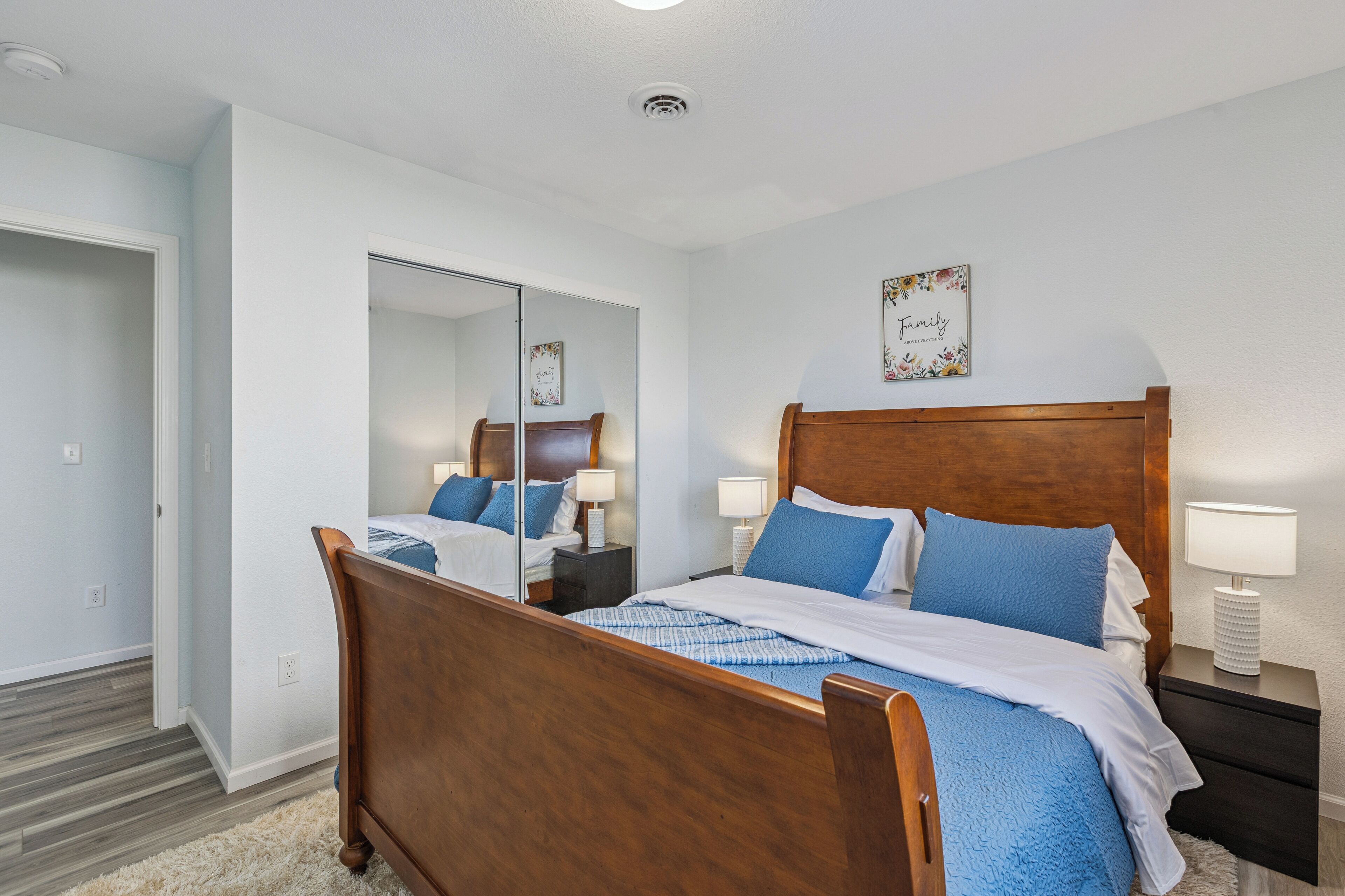 Un dormitorio ordenado con cama de madera, mesitas de noche y un espejo.