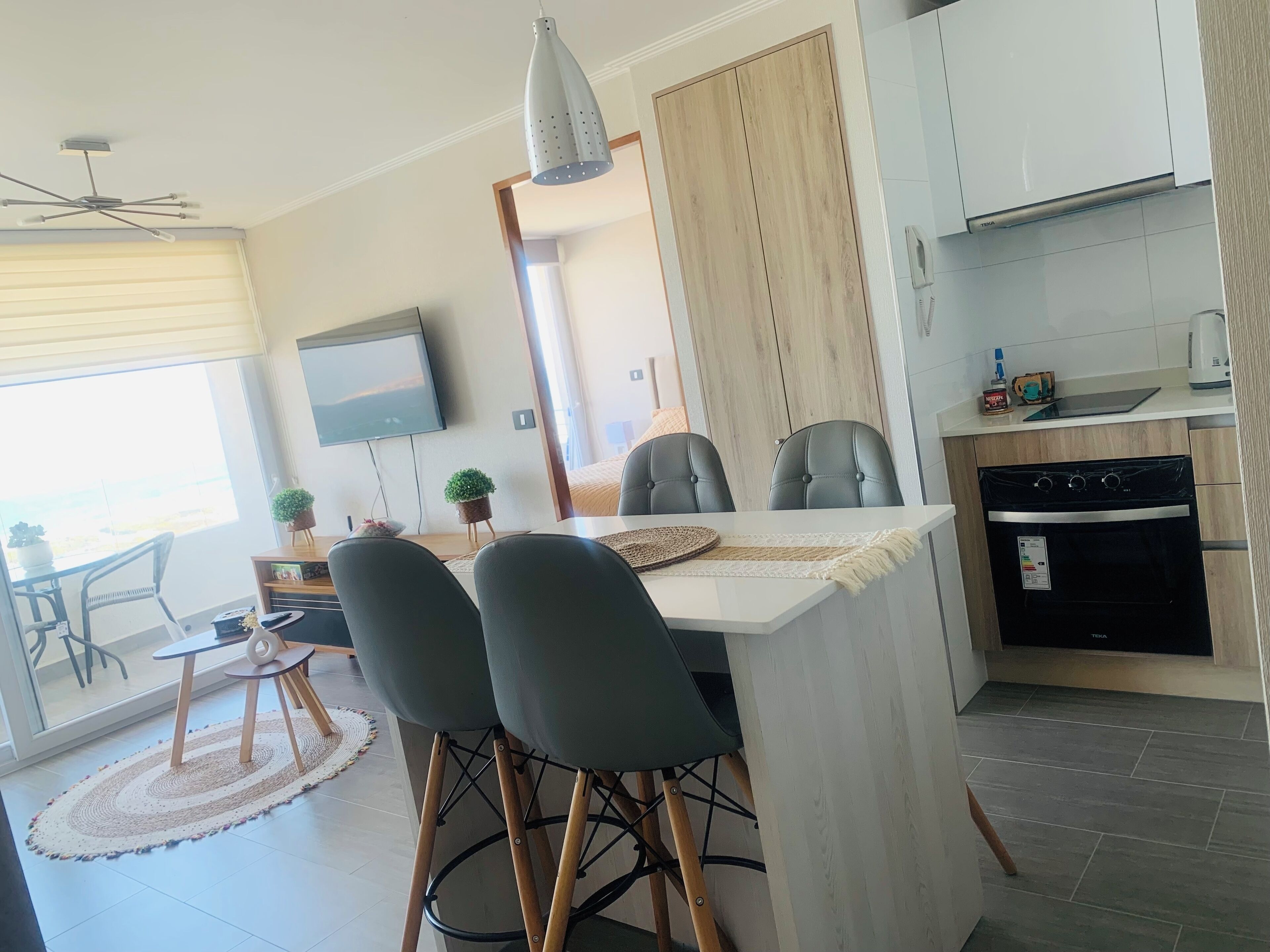 A modern kitchen with a built-in oven and a dining area with a table and chairs.