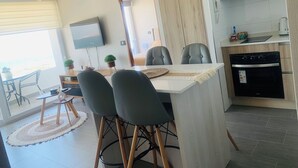 A modern kitchen with a built-in oven and a dining area with a table and chairs. - Espectacular and Luminous Apartment face to face sea view in Iquique (Iquique)