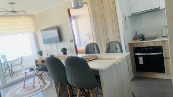 A modern kitchen with a built-in oven and a dining area with a table and chairs.