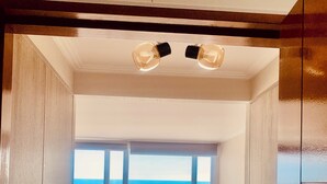 A bedroom with a bed, a window with a view of the ocean, and a ceiling light fixture. - Espectacular and Luminous Apartment face to face sea view in Iquique (Iquique)
