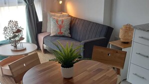 Un comedor con una mesa redonda de madera, cuatro sillas acolchadas y una planta en maceta en el centro.